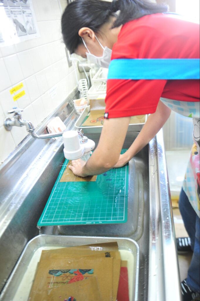 渡口真央（とぐちまお）さんがのりを洗い落としている写真