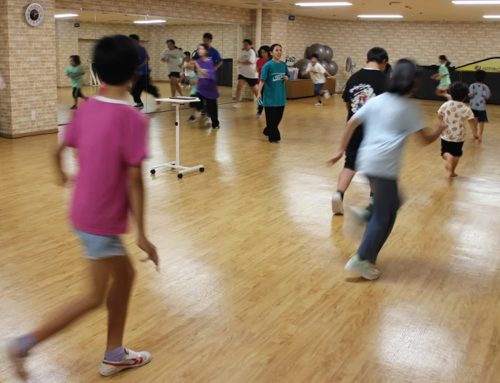 疾走する子どもたちに呼び掛ける新城さん＝2025年8月9日＝北谷町北前のハンビータウン2階スタジオ